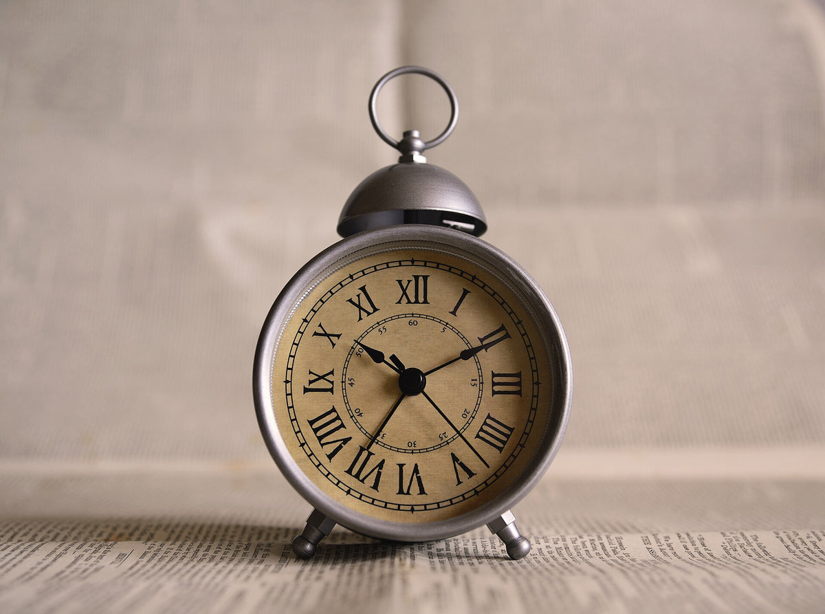 Close-up of the Roman numerals on an alarm clock, a reminder that a steady daily time matters more than the hour