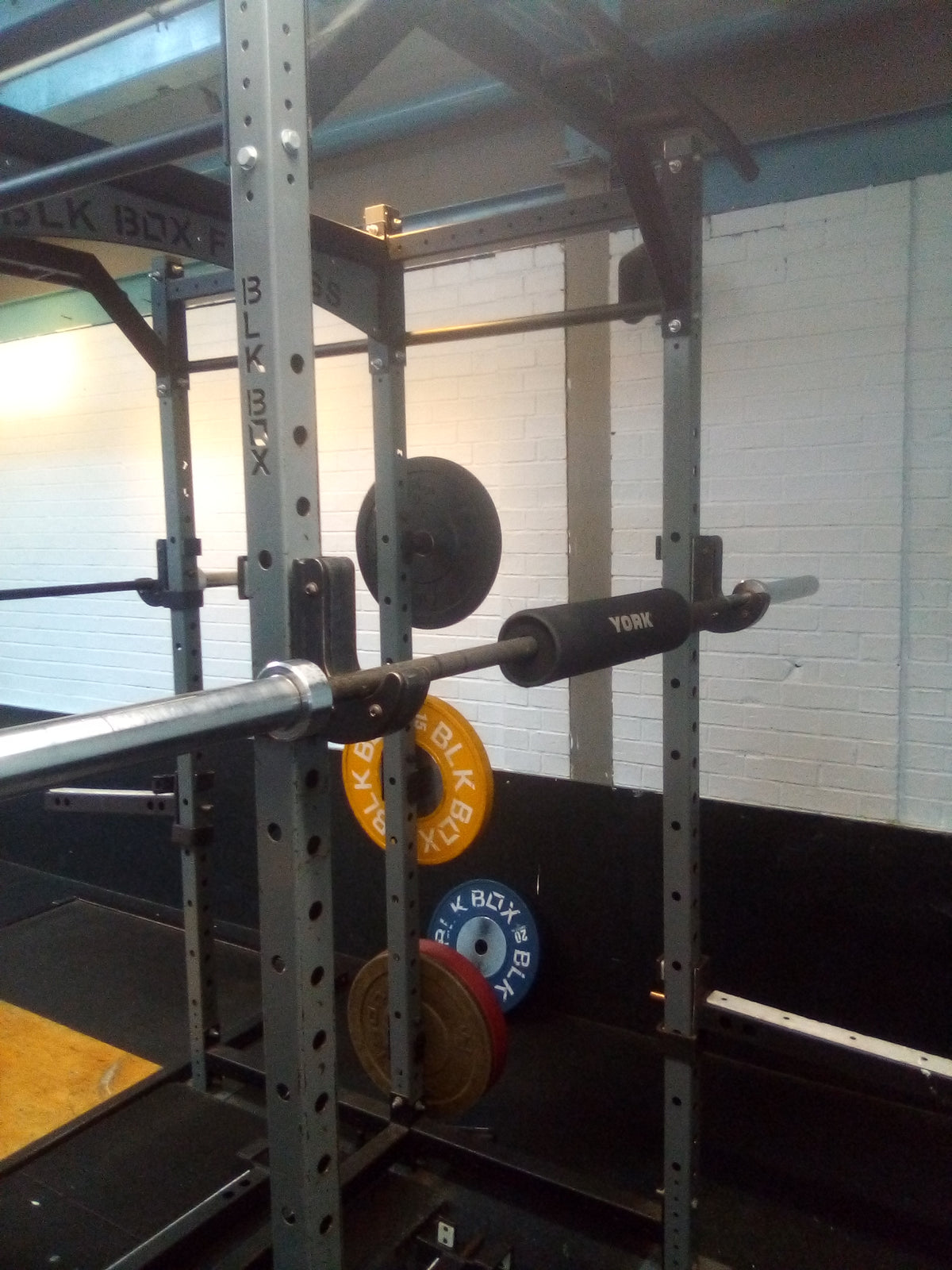 A barbell resting in a squat rack, because creatine only helps body composition when paired with strength training