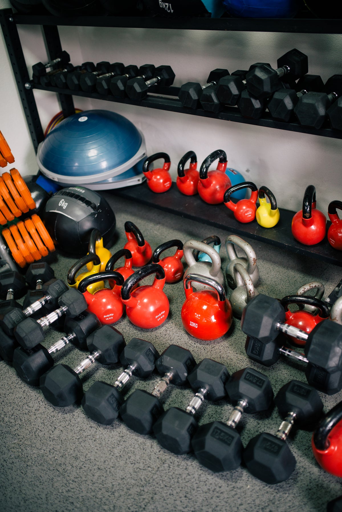 Brightly colored kettlebells and dumbbells lined up on a gym floor, simple tools for strength training after menopause