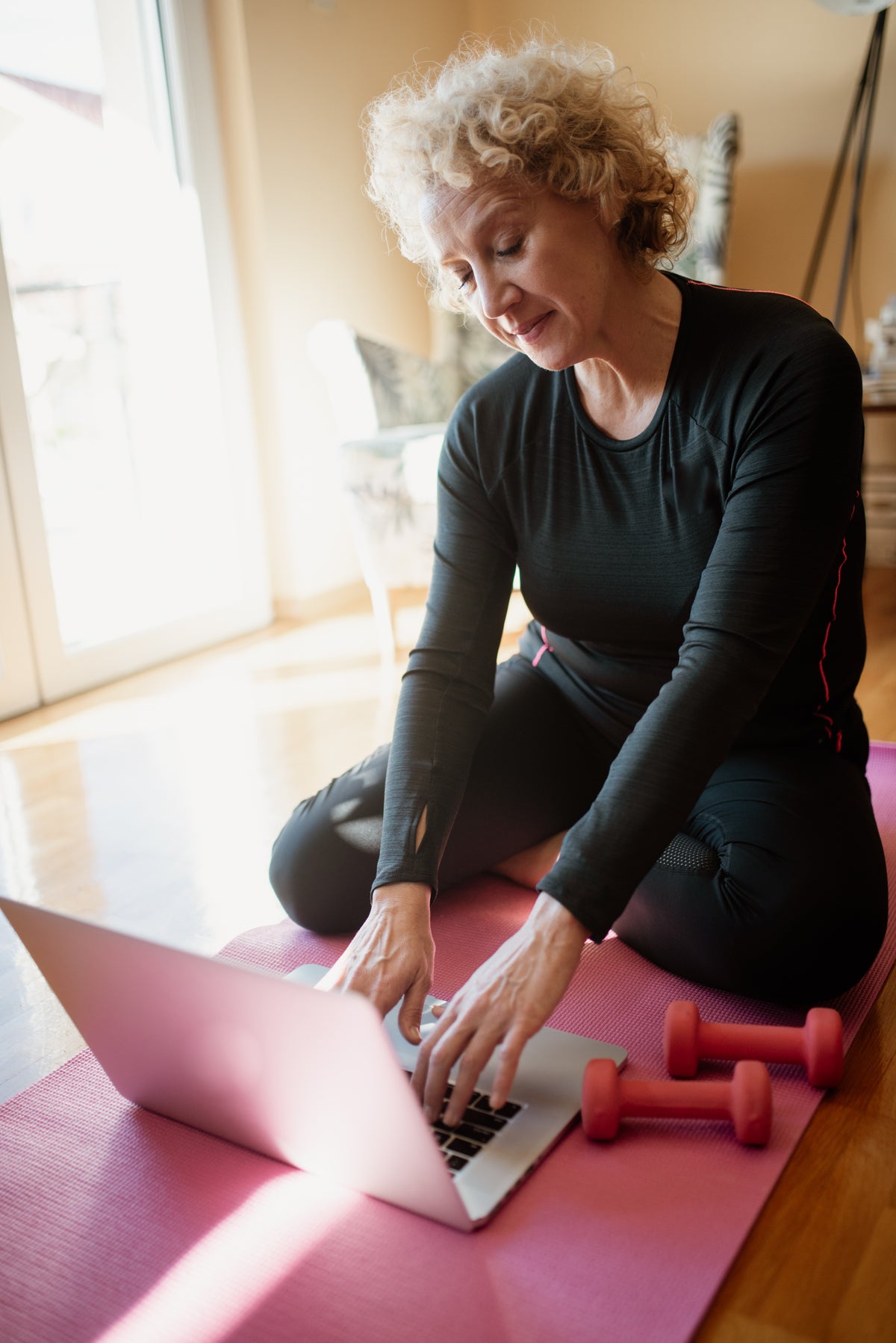 An older woman lifting dumbbells at home, the kind of training that made creatine work in menopause trials