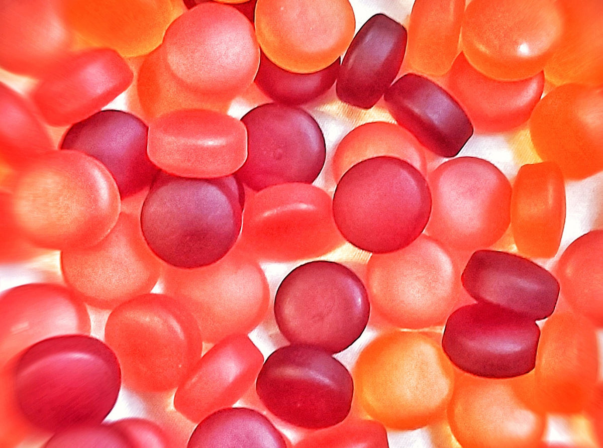 A pile of orange and yellow supplement gummies, the same chewy format most big-brand fiber gummies use