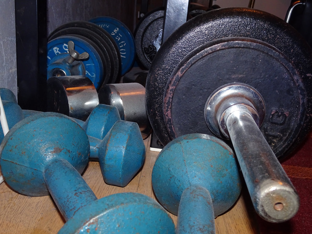 Dumbbells, a kettlebell, and weight plates on a gym floor, the training creatine timing studies used