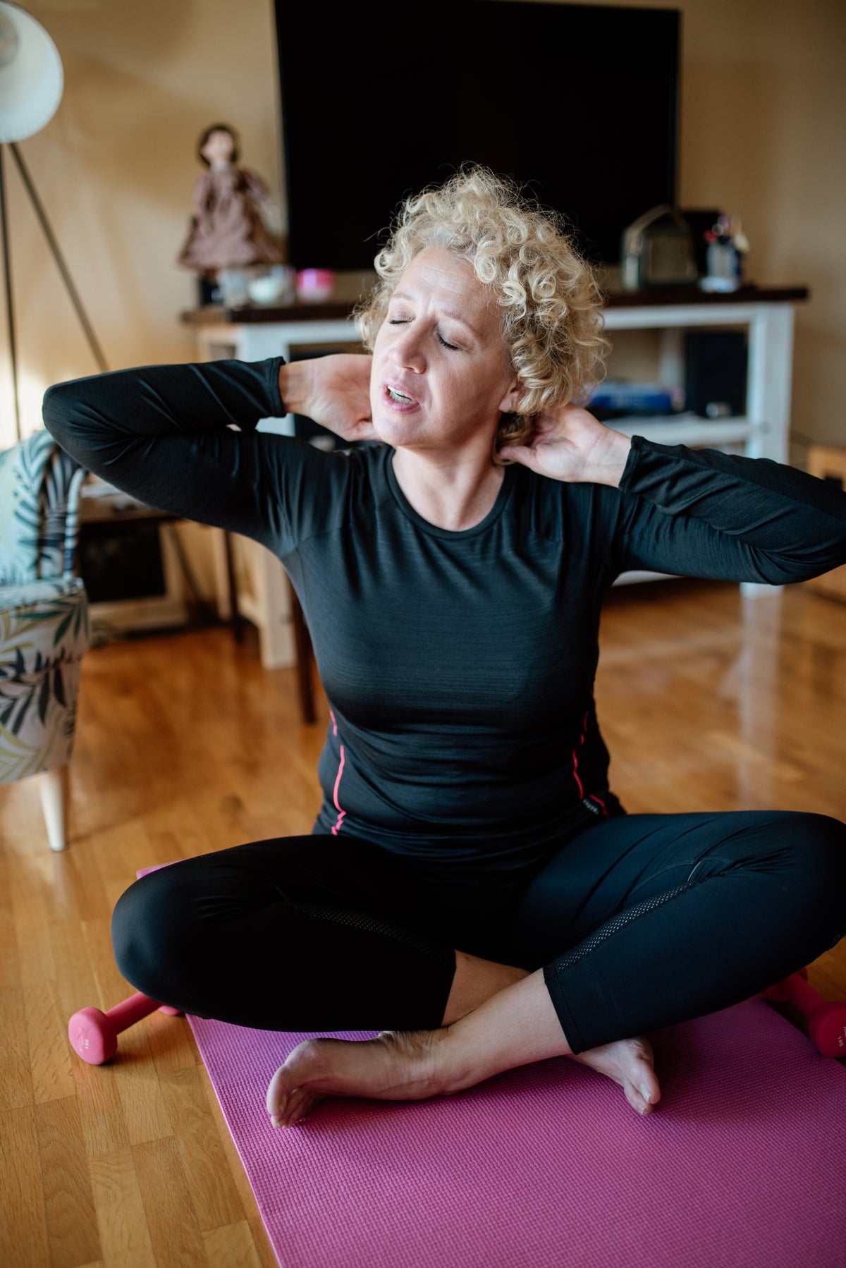 A woman stretching and relaxing at home in her living room, with no gym equipment in sight