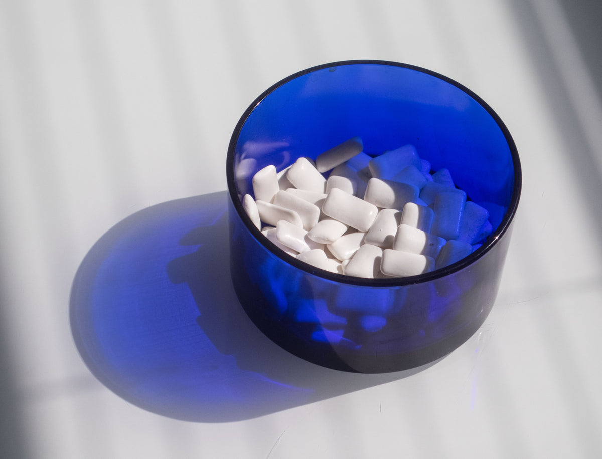 A blue bowl of xylitol chewing gum pellets, a common source of swallowed air and gas-making sugar alcohols