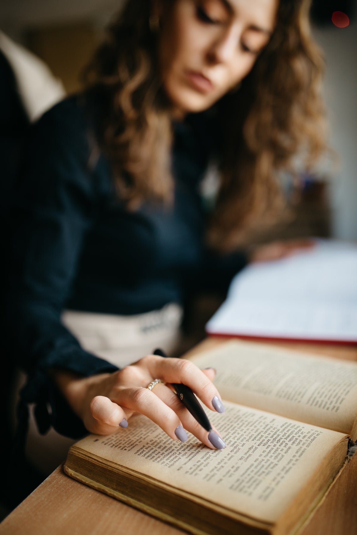 A young woman reads a book and takes notes at a wooden desk, the kind of memory task creatine trials measure