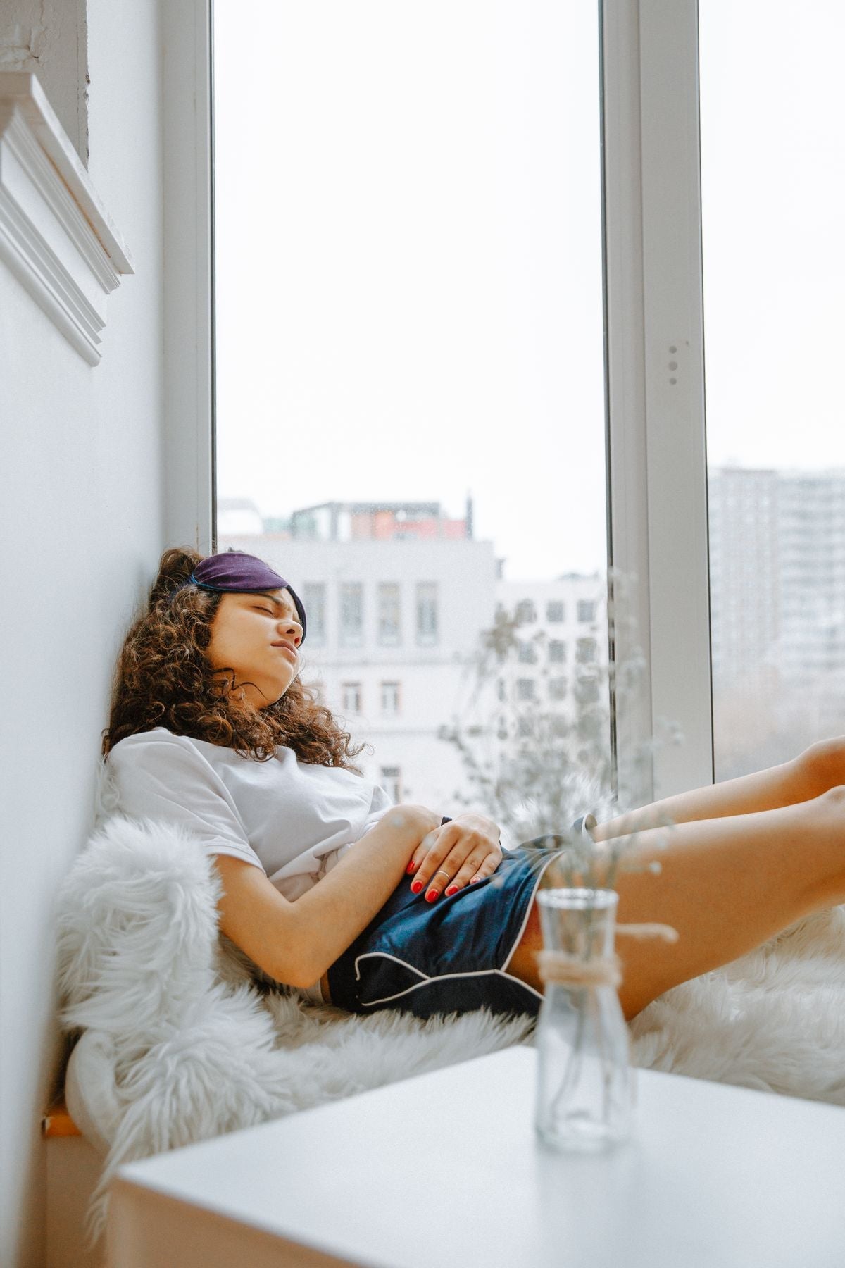 Woman resting on a windowsill with one hand on her belly